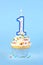 Iced birthday cupcake with with lit number 1 candle