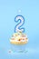 Iced birthday cupcake with with lit number 2 candle