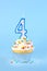 Iced birthday cupcake with with lit number 4 candle