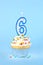 Iced birthday cupcake with with lit number 6 candle