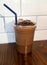 Iced chocolate topped with chocolate chunk in takeaway glass isolated on wooden table