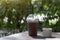 Iced cocoa in plastic glass and tubes with tiramisu cake in white cup paper  on wooden table.