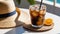 Iced coffee with milk in a glass and straw hat on wooden table. Summer vacation concept