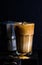 Iced coffee with milk in a tall glass, moka pot, black background