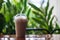 Iced coffee mug on table with natural green blurred background.