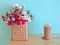 Iced coffee in plastic cup and flowers in basket on the wood table