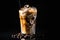 Iced coffee with swirling milk in a glass, coffee beans scattered