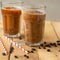 Iced coffee in transparent glasses with ice and straws, on a wooden background, a cooling drink