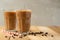 Iced coffee in transparent glasses with ice and straws, on a wooden background, a cooling drink