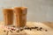 Iced coffee in transparent glasses with ice and straws, on a wooden background, a cooling drink