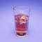 Iced colored soft drink in transparent glass on purple background