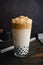 Iced Dalgona Coffee with Boba in a Pint Glass on a Dark Background