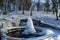Iced fountain in the park on a winter sunny day. Fountain with frozen water