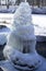 Iced fountain in the park on a winter sunny day. Fountain with frozen water