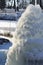 Iced fountain in the park on a winter sunny day. Fountain with frozen water