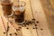 Iced iced coffee in large transparent glasses, poured over milk, with coffee beans on a wooden background, summer cooling drink