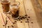 Iced iced coffee in large transparent glasses, poured over milk, with coffee beans on a wooden background, summer cooling drink,