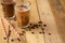 Iced iced coffee in large transparent glasses, poured over milk, with coffee beans on a wooden background, summer cooling drink,