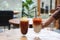 Iced milk tea and Iced coffee with orange on table and blurred background.