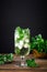 Iced mint tea, refreshing herbal drink in a glass with ice and fresh leaves on dark background