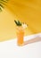Iced pineapple punch cocktail in glass on orange background. summer drink