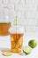 Iced tea in a plastic cup with straw with slice of lime. White w