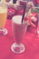 Iced watermelon juice glass on a red table in restaurant and cafe interior. Tropical island of Bali, Indonesia. Woman