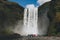 ICELAND - 20 JUNE 2018: tourists walking near waterfall Skogafoss under bright