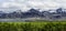 Iceland panorama snow coverd mountain range beneath cloudy sky green meadows bushes depth of field