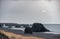 Iceland Seashore with Black sand on beach and rocks. Waterfall in Background