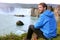 Iceland tourist relaxing by waterfall Godafoss