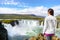 Iceland Travel. Tourist woman by Godafoss waterfall. Happy young woman tourists enjoying icelandic nature landscape