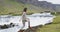 Iceland travel travel video. Woman walking by waterfall on Iceland. Girl tourist in casual clothing visiting icelandic