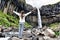 Iceland. Woman enjoying majestic Svartifoss waterfall. Female is visiting famous tourist attraction of Iceland