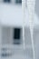 Icicle on top of roof with house in background