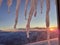 Icicles and dramatic sunset in the mountain. Cloudy sky at sunset. High mountain snowy landscape
