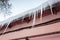 Icicles hang on the roof side over pink wall