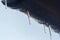 Icicles hanging from roof of house. Winter concept. Closeup danger icicles. Frozen climate pattern. Frost winter