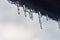 Icicles hanging from roof of house. Winter concept. Closeup danger icicles. Frozen climate pattern. Frost winter