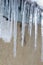 Icicles on an old, rusty, rural roof. Clay wall