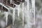 The icicles on roof at end of winter. Thaw, melting snow and ice on spring. Drops of water slowly fall of a roof. Blurred