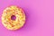 Icing donut on a pink background with text space. Flat lay, purple mockup, template. Yellow donut with multicolored sprinkles. Unh