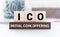 ICO abbreviation stands for Initial Coin Offering on wooden blocks, yellow background. Cryptocurrencies concept