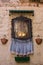 Icon of Mother of God with floerw pots and candles outdoor. Religion and faith concept. Ancient icon in italian architecture.