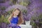 Iconic blond chestnut cute fancy dressed girl posing sit in center of lavender meadow field in velvet violet airy dress with baske