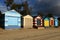 Iconic colorful beach boxes light by the late afternoon sun as a storm approaches