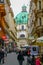 Iconic green dome of St Peter`s church at end of narrow street lined by traditional buildings