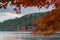 An iconic red gate of Hakone jinja shrine standing in Lake Ashi with blurred red maple leaves
