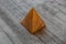 Iconic representation of a perfect isolated brown pyramid on a wooden surface