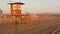 Iconic retro wooden orange lifeguard watch tower on sandy california pacific ocean beach illuminated by sunset rays